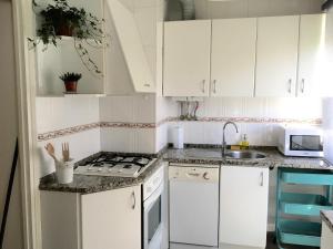 una pequeña cocina con armarios blancos y fregadero en Lisbon Woods House II, en Lisboa