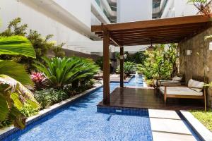 an outdoor pool with a wooden pergola at Apartamento Pé na Areia 212 - Apartamento Beira Mar 210 - Cabo Frio in Cabo Frio