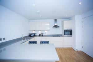 a kitchen with white cabinets and a white counter top at PRESTIGE 2 BED BALCONY APARTMENT in Abbey Wood +35 photos