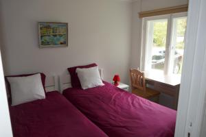 - une chambre avec un lit doté de draps violets et une fenêtre dans l'établissement Kärdla Holiday House, à Kärdla