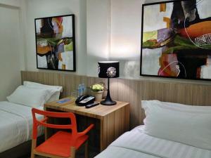 a room with two beds and a desk with a lamp at Z Pad Residences in Tacloban
