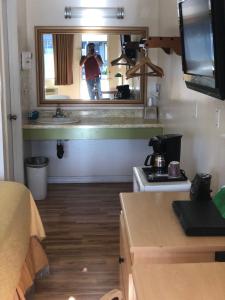 Ein Mann fotografiert eine Küche mit einem Spiegel in der Unterkunft Kelseyville Motel in Kelseyville