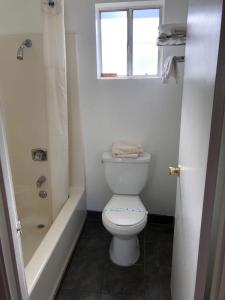 La salle de bains blanche est pourvue de toilettes et d'une fenêtre. dans l'établissement Kelseyville Motel, à Kelseyville