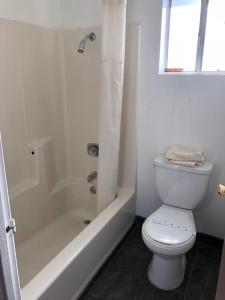 La salle de bains blanche est pourvue de toilettes et d'une baignoire. dans l'établissement Kelseyville Motel, à Kelseyville