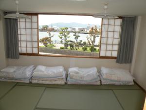 a room with a window with a row of pillows at Business Hotel Minshuku Minato in Tokushima