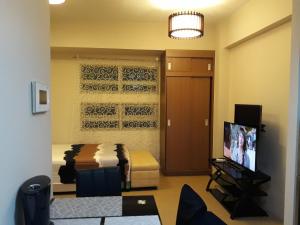 um quarto com uma cama, uma televisão e um sofá em 150 Newport City Condo - near NAIA T3 AIRPORT MANILA em Manila