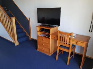 a room with a desk with a television and a staircase at The Anchor Inn Beachfront Motel in Kaikoura