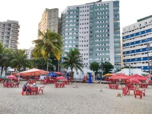 a beach with red chairs and umbrellas and buildings at Edifício Lord - APTO in São Vicente