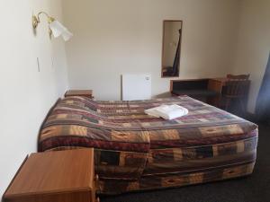 a bedroom with a bed with a blanket and a table at Mt Cook View Motel in Fox Glacier