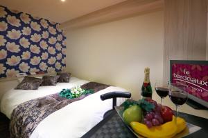 a room with a bed with a bowl of fruit and wine glasses at HOTEL le bordeaux -ル ボルドー- in Kurume