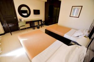 Hotel Tavern Surigao في مدينة سوريجاو: غرفة فندقية بسريرين وطاولة