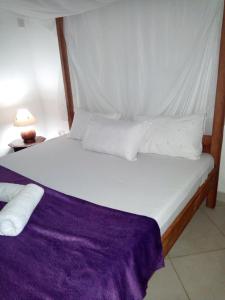 1 cama con sábanas blancas y almohadas en una habitación en Fast Care Villa Bavaria en Mombasa