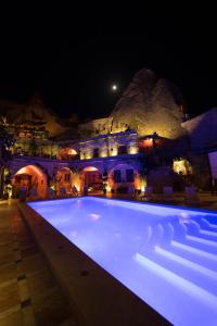 a swimming pool at night with a mountain in the background at Local Cave House in Göreme