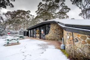 a stone building with a picnic table in the snow at Discovery Parks - Cradle Mountain in Cradle Mountain +44 photos