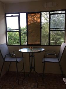 a table and two chairs in a room with windows at Casa Mokoron in Managua