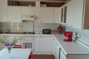 una cucina con armadi bianchi e un apparecchio rosso di Gino's House a Gubbio