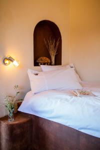 Krumhuk Guestfarm في Willemshof: سرير مع اللوح الأمامي الخشبي والشراشف البيضاء