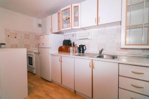 a white kitchen with a sink and a refrigerator at Fri Apartment in Piran