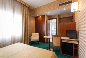 a hotel room with a bed and a desk with a television at Millennhotel in Bologna