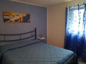 um quarto com uma cama com um edredão azul e uma janela em Casa Loredana em Scauri
