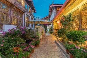 an alley with flowers and an umbrella and buildings at Lijiang Sunshine Nali Inn in Lijiang