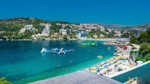 a beach with people and a boat in the water at Hotel Vis in Dubrovnik