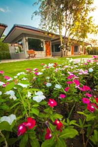 ogród z różowymi i białymi kwiatami przed domem w obiekcie Villa De Bua Resort Nan w mieście Nan