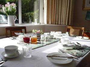 a table with a white table cloth and dishes on it at Honey Lodge in Broadstone