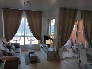 ein Wohnzimmer mit einem Sofa und zwei großen Fenstern in der Unterkunft Casa Playa Sotavento in Costa Calma
