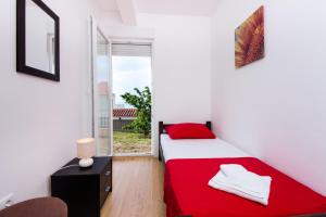 a bedroom with a red bed and a window at Apartment Jusepe in Trogir