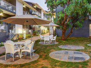 a patio with tables and chairs and an umbrella at Oceans 7 Ashwem in Mandrem