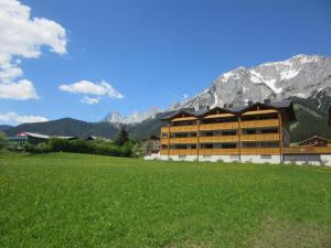 um edifício num campo com montanhas ao fundo em Apartment Coley em Ramsau am Dachstein