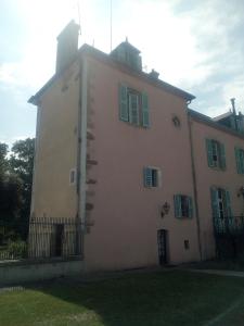 un grande edificio bianco con finestre con persiane verdi di La tour du Roy a Villeneuve-sur-Allier