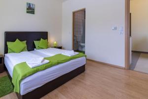 um quarto com uma cama grande e almofadas verdes em Tölgyfa Vendégház em Kiskorös