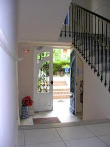 a hallway with a white door and stairs with a vase of flowers at Hotel Le Havre Bleu in Beaulieu-sur-Mer