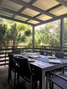 einen Tisch mit Stühlen und Weingläsern auf einer Terrasse in der Unterkunft Mignon Cottage 9 Noongah Terrace in Crescent Head