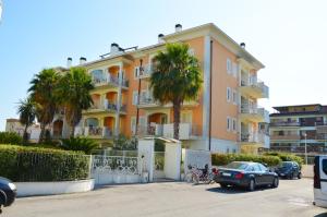 un edificio con palmeras y coches aparcados en un aparcamiento en Giardino sul mare en San Benedetto del Tronto