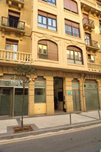 un edificio amarillo con un árbol delante de él en Pensión Aia, en San Sebastián