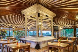 ein Restaurant mit Holztischen und einer großen Decke in der Unterkunft Jambuluwuk Convention Hall & Resort Puncak in Puncak