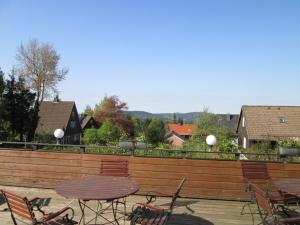 eine Terrasse mit Tischen und Stühlen und einem Holzzaun in der Unterkunft Hotel Skandinavia in Sankt Andreasberg