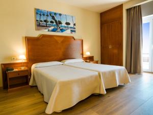 um quarto com uma cama grande e uma cabeceira em madeira em Hotel Monarque El Rodeo em Marbella