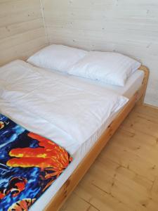 niepościelone łóżko w pokoju z drewnianą podłogą w obiekcie Alga w Sarbinowie