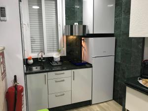 een keuken met witte kasten en een koelkast bij Apartamento Atrapasueños in Cáceres