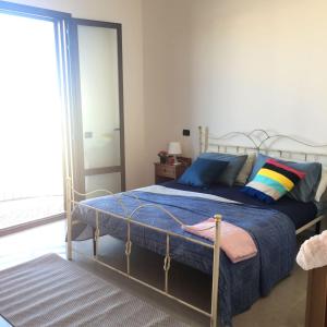 ポルト・チェザーレオにあるCasa Vacanza Porto Cesareoのベッドルーム1室(青いシーツとカラフルな枕が備わるベッド1台付)