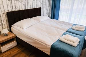 1 dormitorio con 1 cama con 2 toallas en Apartamenty ZEFIR - MARINA BORKI, en Augustów