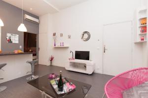 ein weißes Wohnzimmer mit einem Tisch und einem TV in der Unterkunft Marylin 2 pièces 3 étoiles, plein coeur de Cannes, 5mn Palais et plages in Cannes