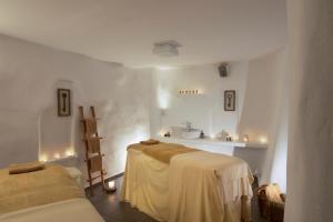 a white room with two beds and a shelf at Santorini Secret Suites & Spa, Small Luxury Hotels of the World in Oia