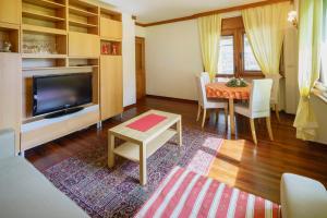 sala de estar con TV, mesa y sillas en Villa Ca Perosego - Stayincortina, en Cortina dʼAmpezzo