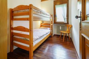 - une chambre avec 2 lits superposés et une chaise dans l'établissement Villa Ca Perosego - Stayincortina, à Cortina dʼAmpezzo