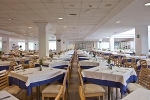 Habitación grande con mesas y sillas con manteles blancos y azules en HYB Eurocalas, en Calas de Mallorca